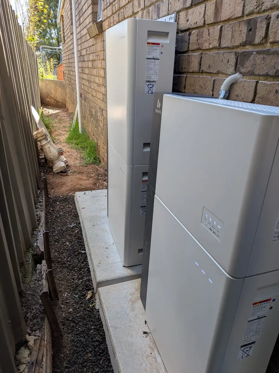 Alpha ESS battery system installed along the side of a brick home